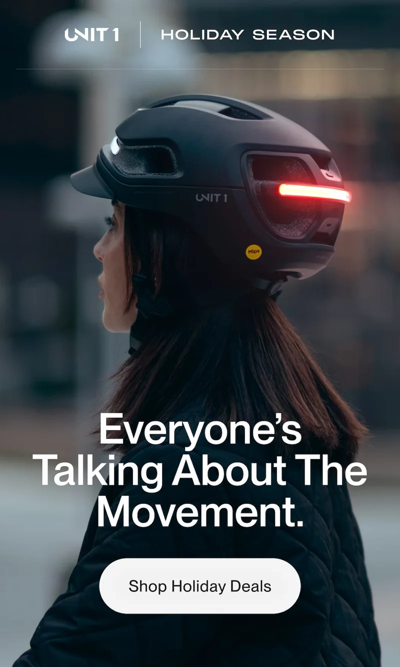 Woman riding at dusk wearing UNIT 1 smart helmet with rear light on. Text: Holiday Season. Everyone’s Talking About The Movement.