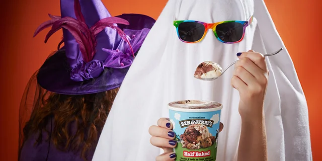 A person dressed as a ghost eats a scoop of Ben & Jerry's Half Baked ice cream.