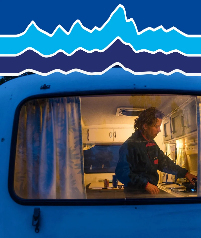 A person cooks on the stove inside a camp trailer.