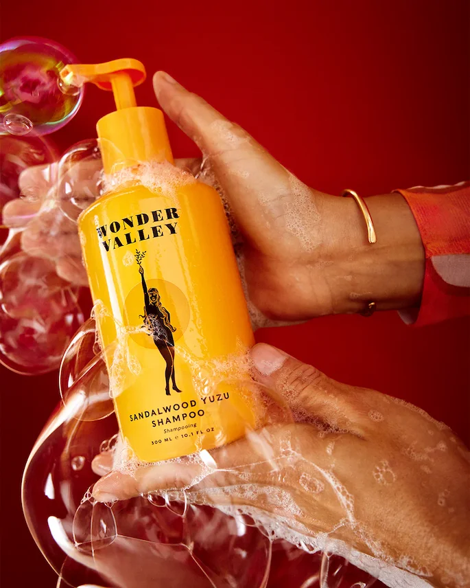 A pair of brown hands holding a bubble-covered yellow bottle