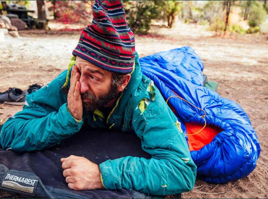 A tired camper waking up in his sleeping bag.