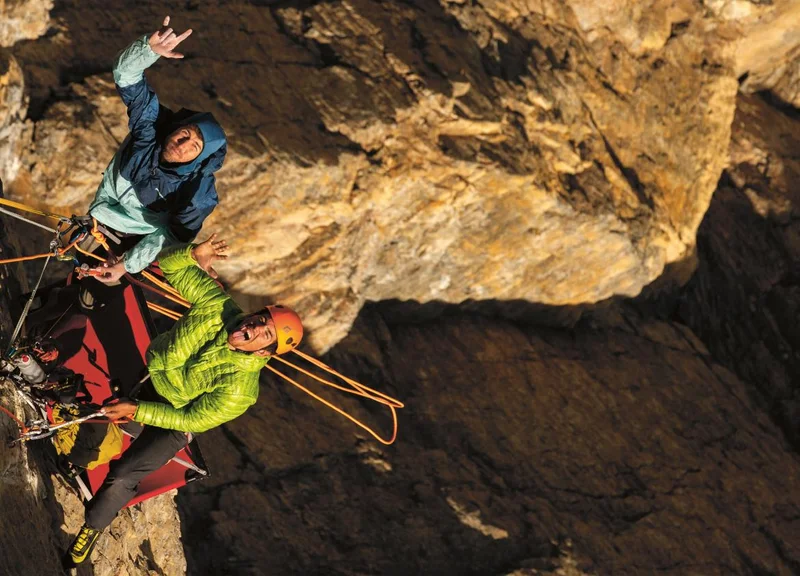 Photo looking down on Sonnie and his climbing partner waving from a belay station.