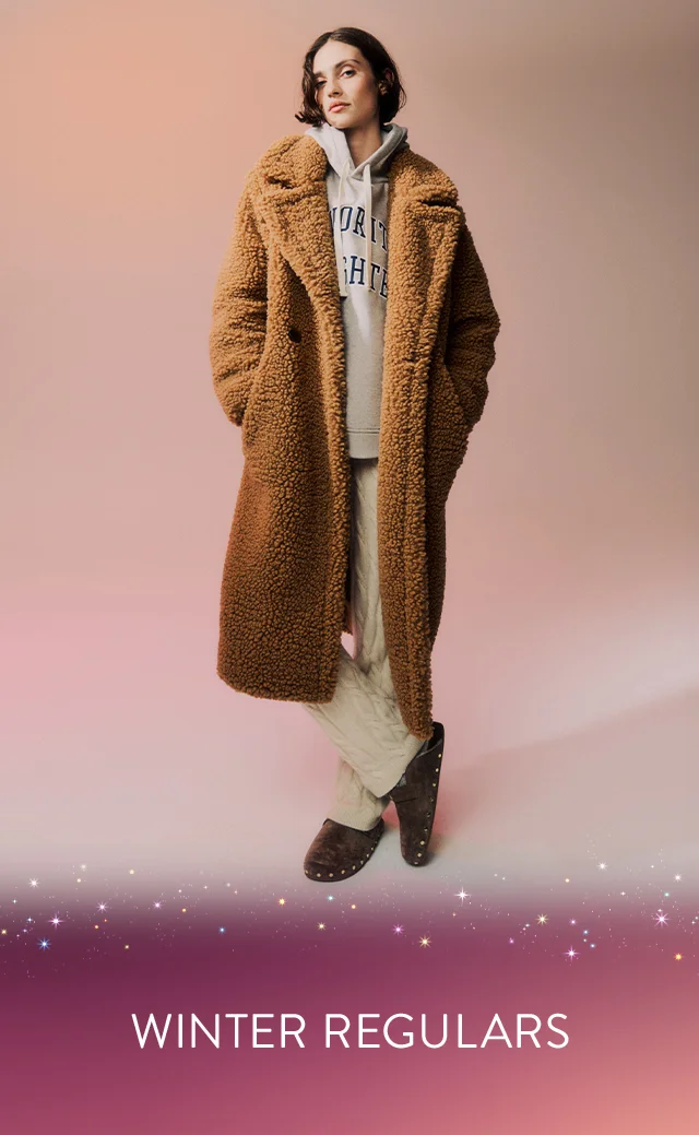 A woman wearing a brown teddy coat with a grey hoodie and knit pants.