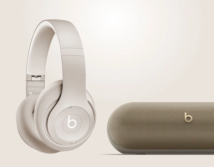 Beats Studio Pro in Sandstone next to Beats Pill in Champagne Gold.