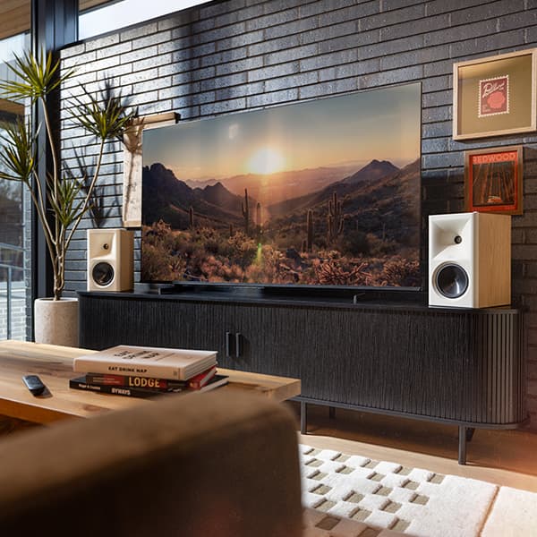 Red Oak Fives II Powered Speakers in a bright, rustic living room, along side a flat screen tv.