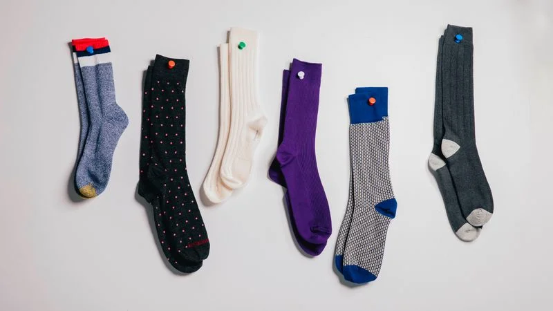 A photo of 6 mens dress socks pinned to a light gray background