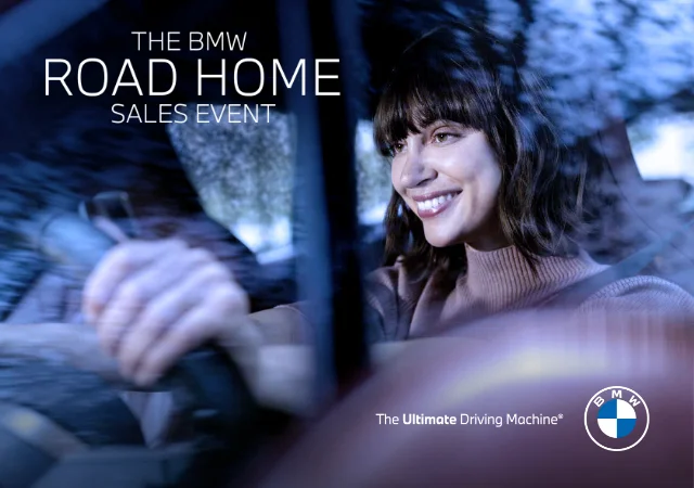 A woman smiling while driving a BMW vehicle. The BMW Road Home Sales Event. The Ultimate Driving Machine®. BMW.