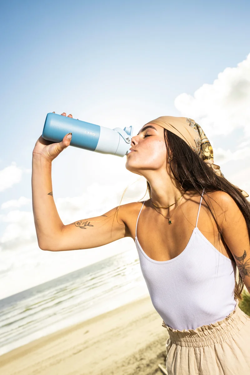woman taking a sip from LARQ Bottle Swig Top 23 oz on beach
