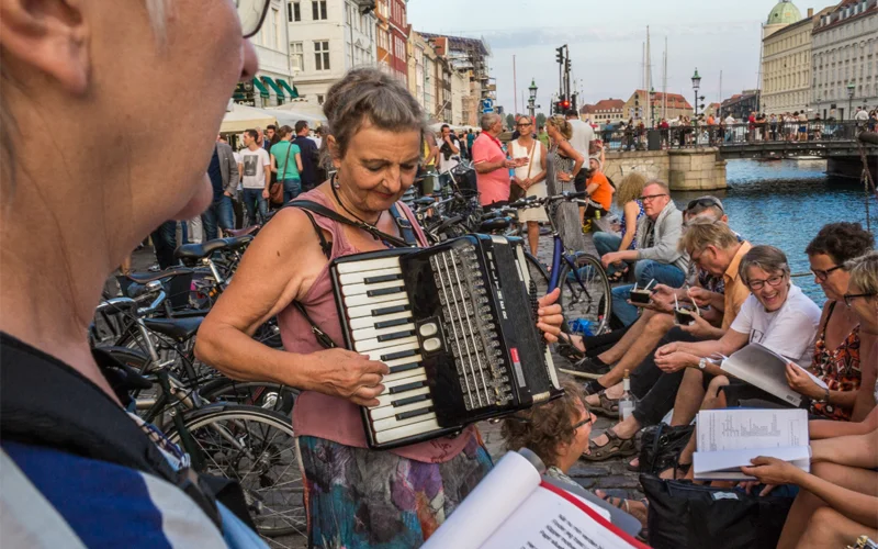 Members of a singles club socialize, sing, and drink on Nyhavn, a street that runs along a canal in Copenhagen, Denmark. Studies suggest that living in a walkable community like this one have enormous benefits for your physical and mental health.