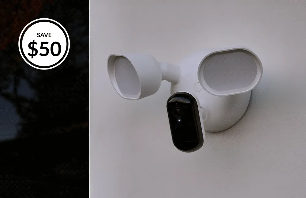Save $50. Arlo Wired Floodlight mounted on the exterior of a home turning on and off.