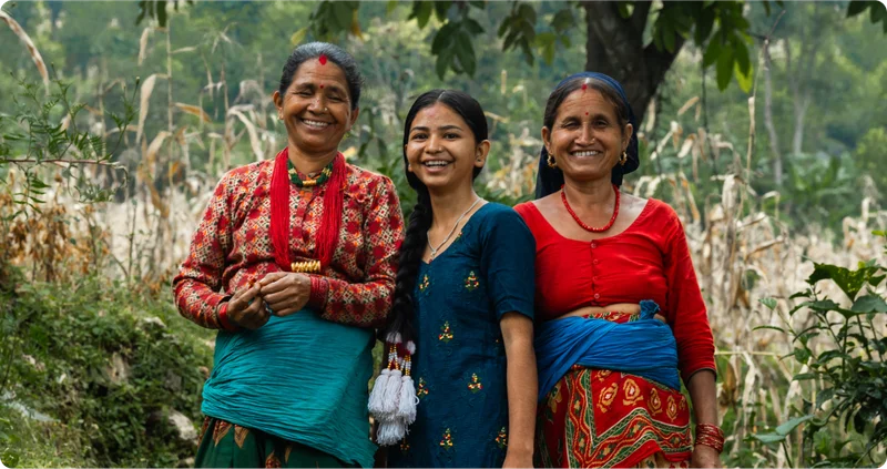 In Nepal, 3 generations of women stand next to each other smiling.