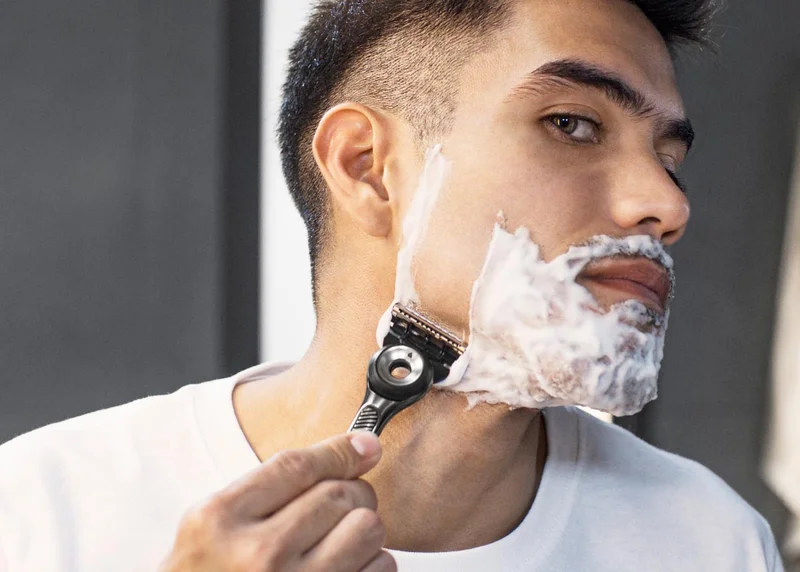 Young man shaving his face