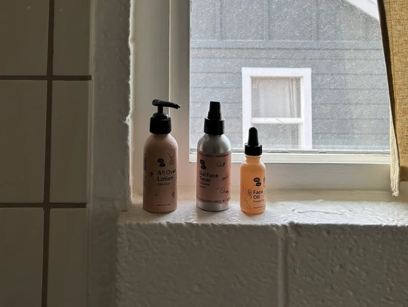Three bottles of skincare products are placed on a windowsill.
