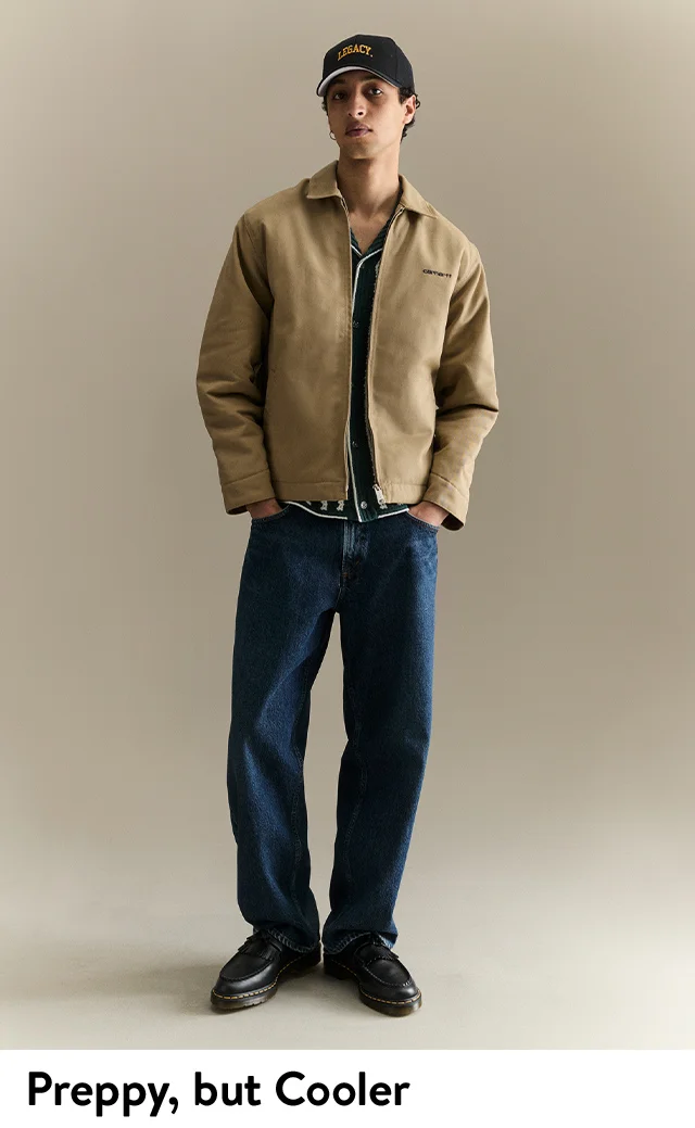 A man wearing a light jacket over a knit shirt and jeans.
