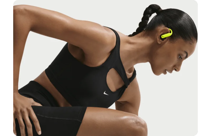 Woman in spanks stretching her legs while wearing Nike Powerbeats Pro 2 earbuds.