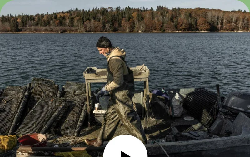 A person in dirty slickers walks on their small boat.