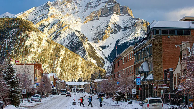 Image description: Three tourists crossing snow-covered main street in Banff, in the winter