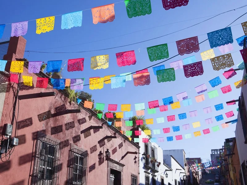 Colourful cut out paper flags hanging above a street.