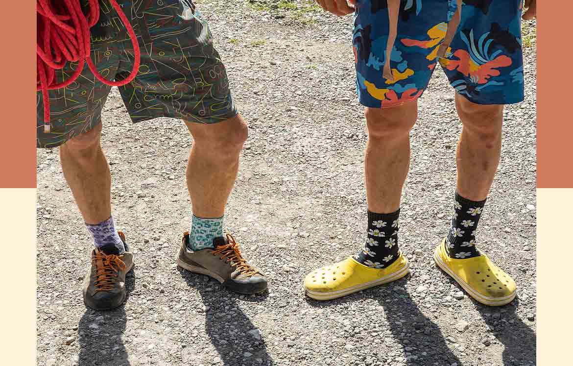 Two people standing in shorts and colorful socks and shoes.