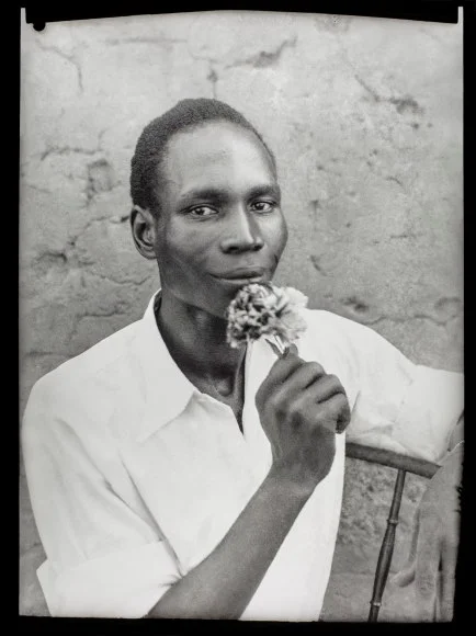 A portrait of a man holding a flower and smiling