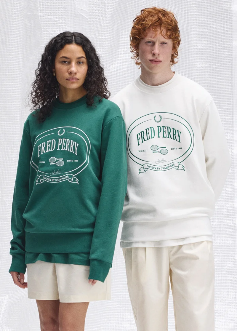 Male and female model stand next to each other wearing matching graphic sweatshirts in green and ecru