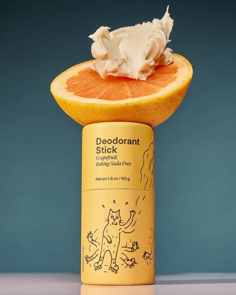 An orange grapefruit deodorant tube balances a grapefruit slice and a schmear of deo