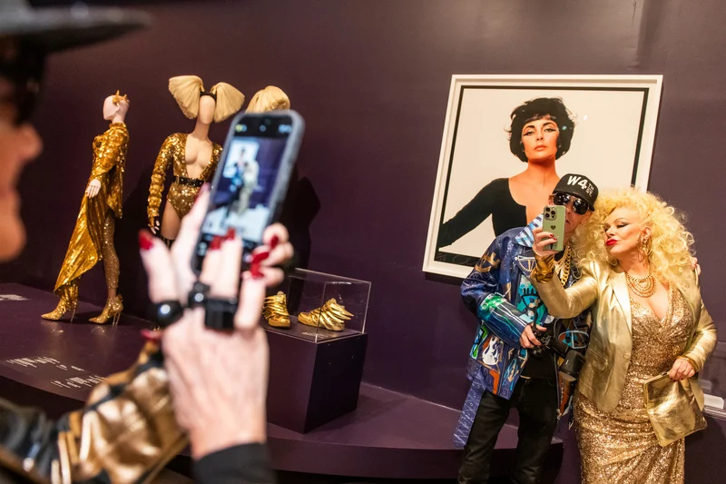 Two people take a selfie in front of a work of art