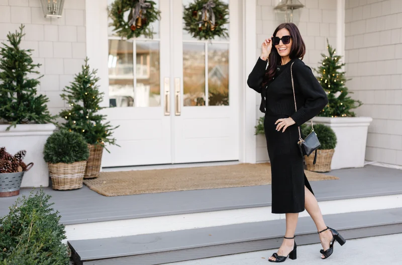 Tori Wesszer wearing black cardigan, skirt and heels stood in front of festive porch