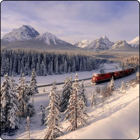 Image Description: Snow-covered landscape with trees and mountains and a red train winding through the scene.
