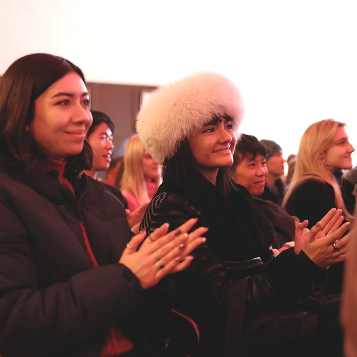 Image of festival attendees cheerfully clapping and smiling.