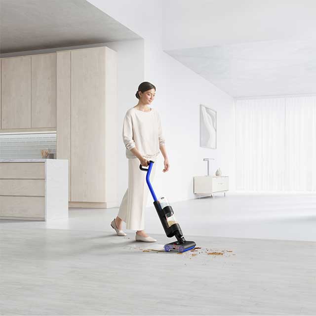 A woman cleaning a large open plan living area with the Dyson WashG1 wet cleaner
