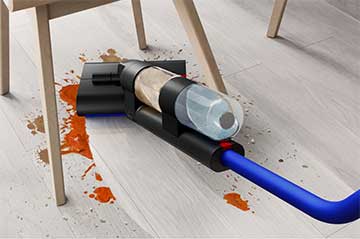 A close-up of the WashG1 cleaning large food spills under a kitchen table