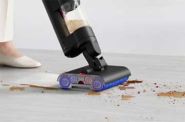 A close-up of cleaner head removing dry dirt and wet mess on a hard floor