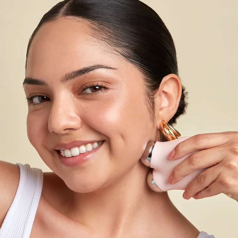 Woman holding MINI+ Device to her cheek to achieve a contoured look.