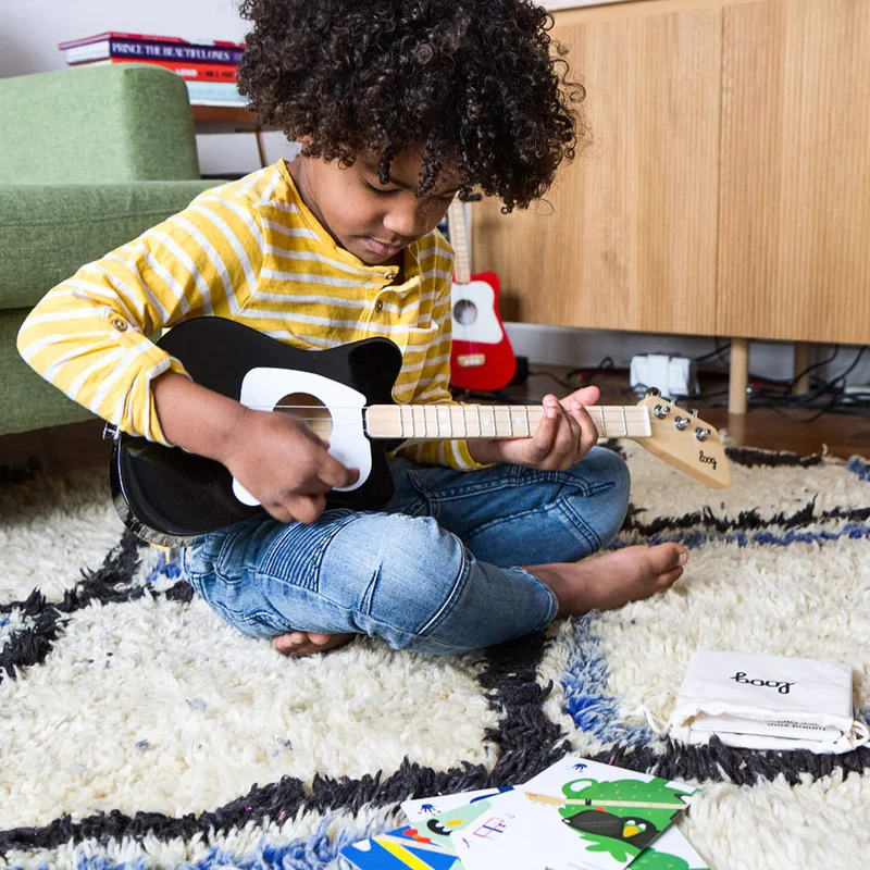 kid playing mini acoustic guitar