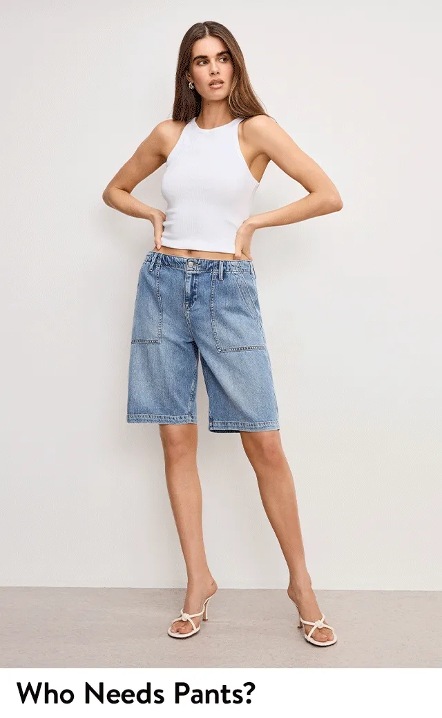 A woman wearing knee-length denim shorts and a white tank top.