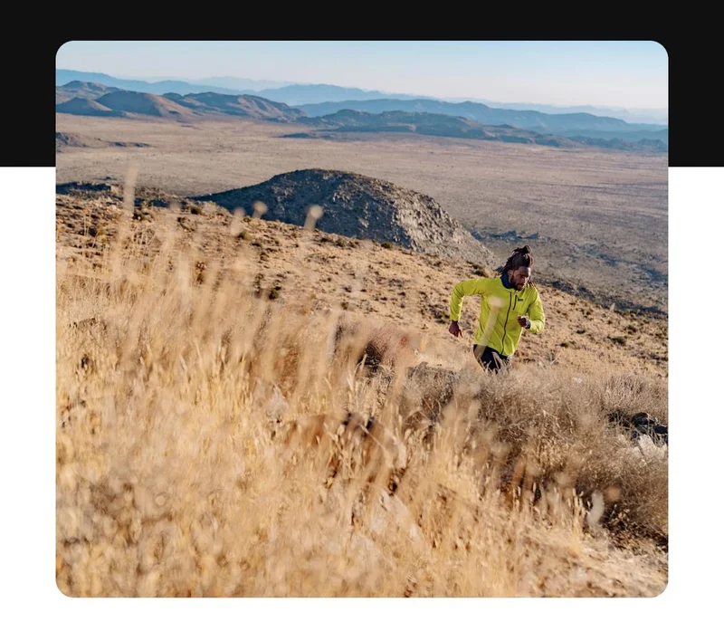 A runner on a trail in a wide open landscape.