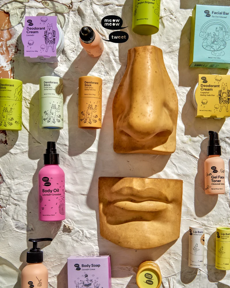 A collection of colorful products on a plaster backdrop with ceramic face features like a nose and lips