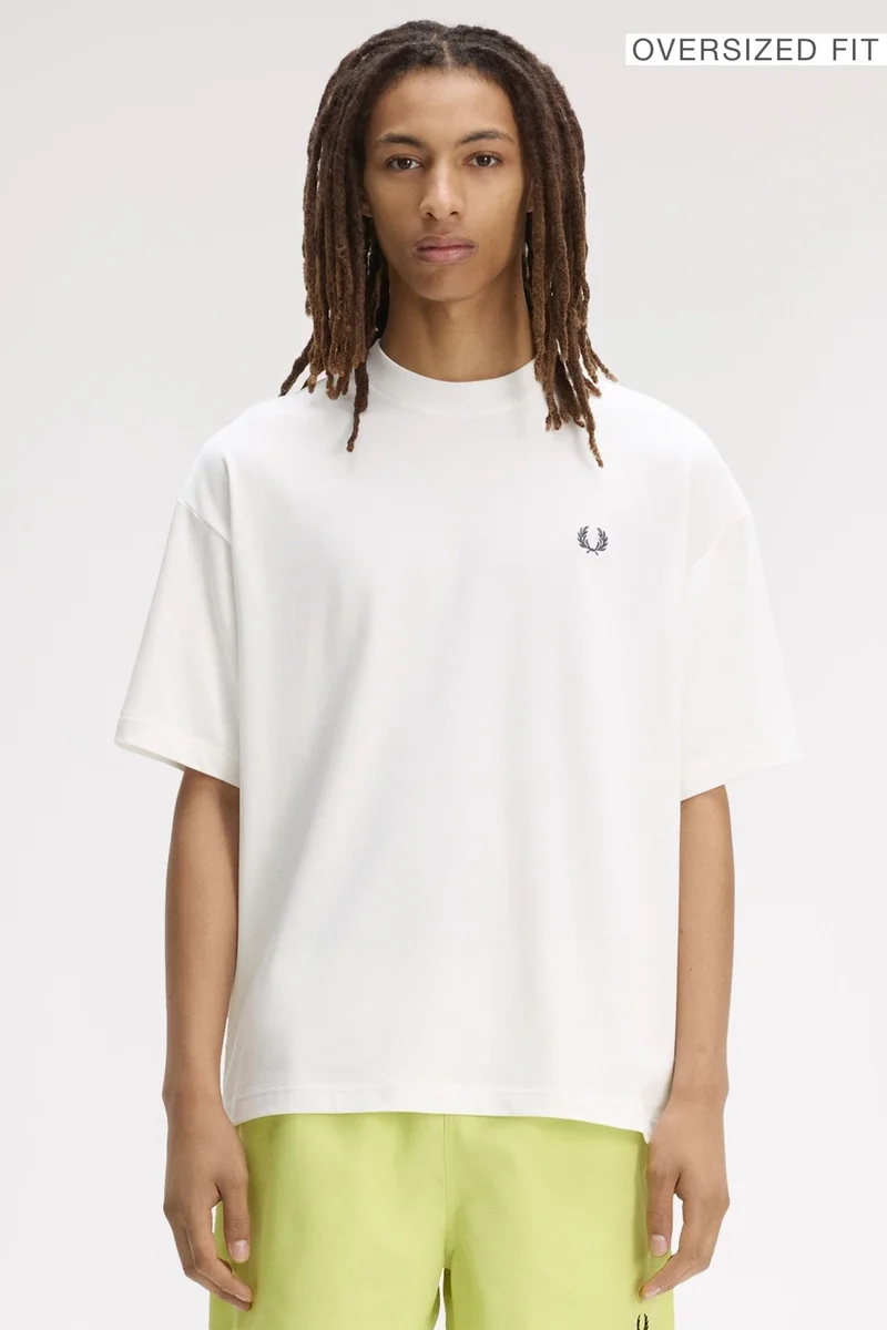 A male model wearing a Fred Perry Back Print Laurel Wreath Oversized T-Shirt in Snow White