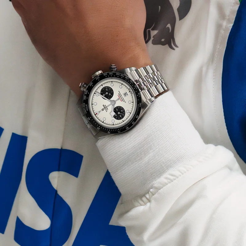 A person wearing a silver, black and white watch on their wrist. A person wearing a silver, black and white watch on their wrist.