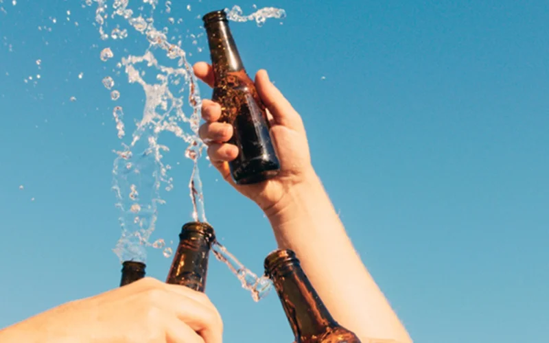 People splash beer bottles in the air.