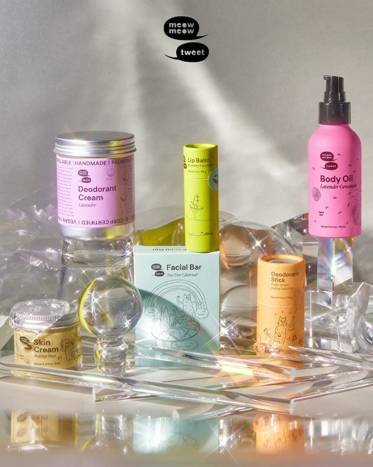 Six different skincare products in different colorful containers are displayed with different clear shaped items that are reflecting and refracting light.