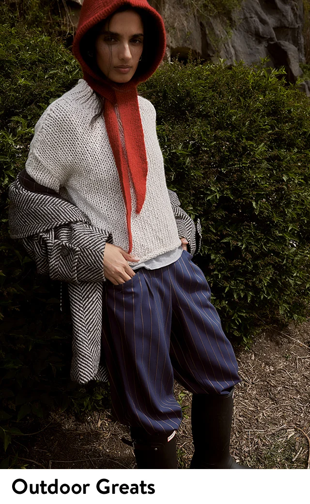 A woman wearing a chunky sweater with a herringbone coat and striped pants.