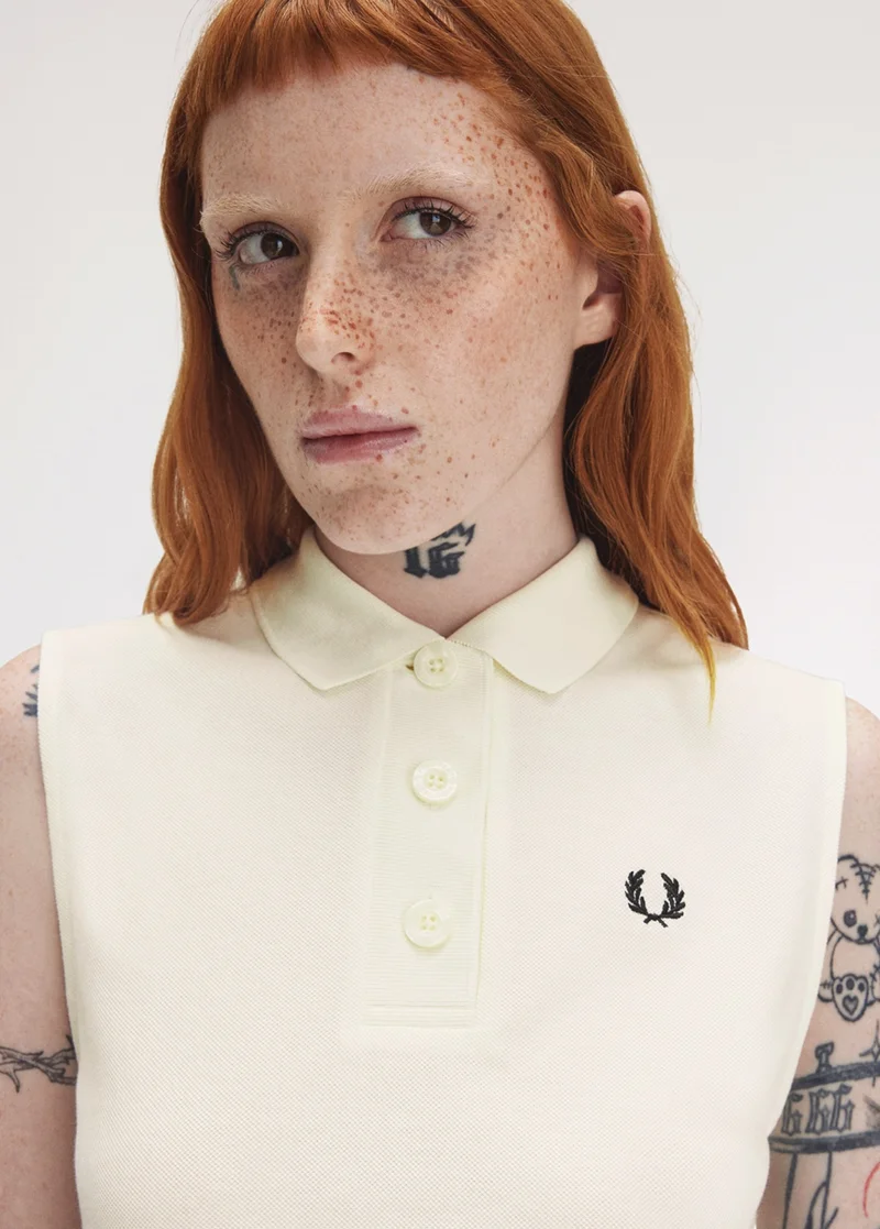 White female model wears a Fred Perry Sleeveless Piqué Shirt in Silky Peach