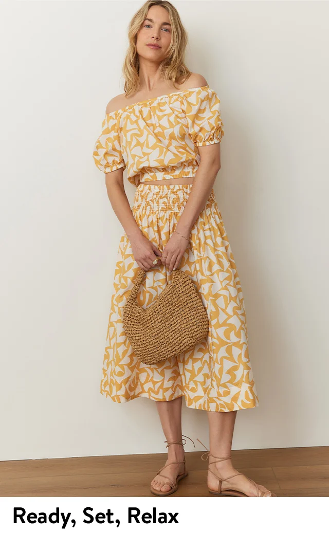 A woman wearing a yellow off-the-shoulder top and a matching midi skirt.