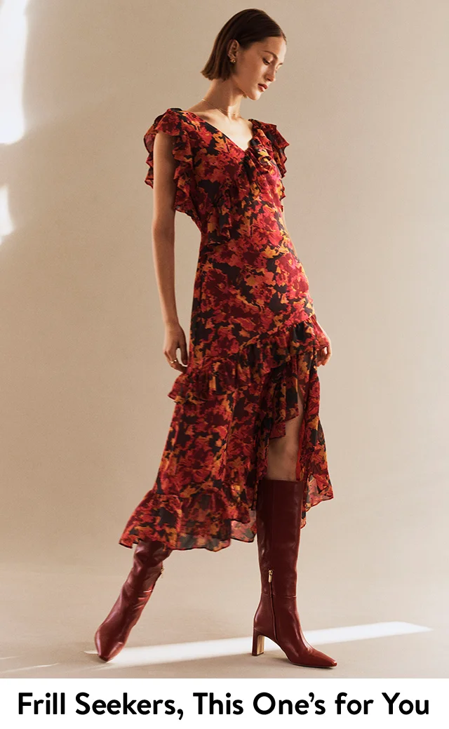 A woman wearing a ruffled floral dress and knee-high boots.