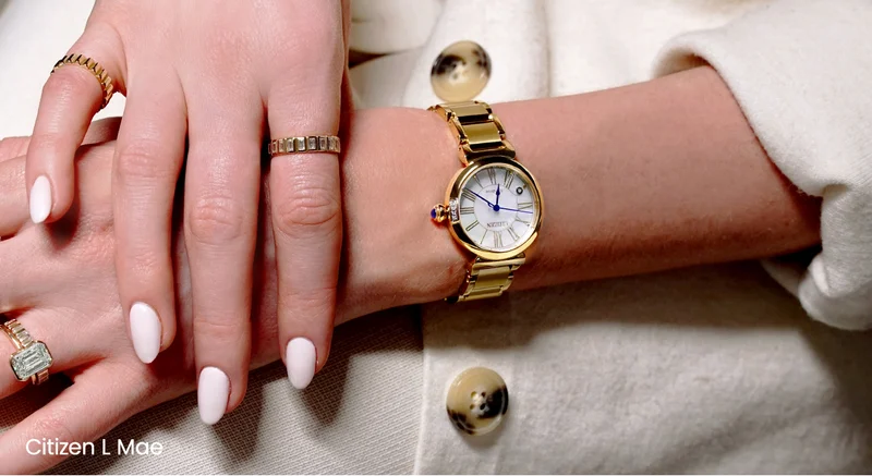 Person with manicured nails wearing rings and the white dial Citizen L Mae