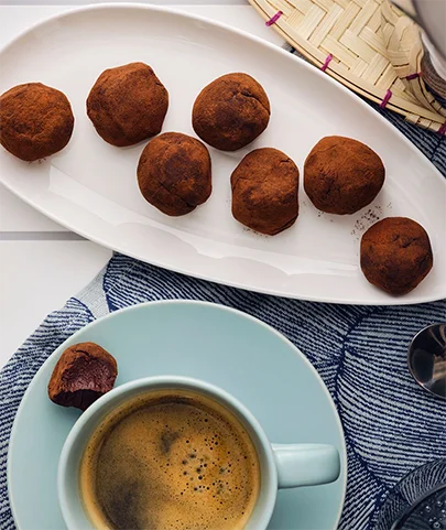 Chocolate truffles on a tray next to a cup of coffee