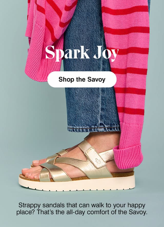 Woman in pink-and-red striped sweater, blue jeans and the Savoy sandal in metallic champagne. Shop the Savoy.