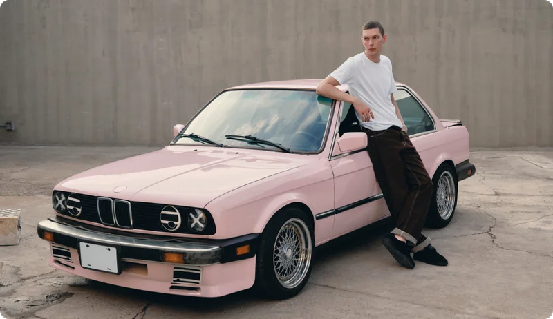 Person leaning on a pink car wearing Oura Ring 4 Ceramic Petal